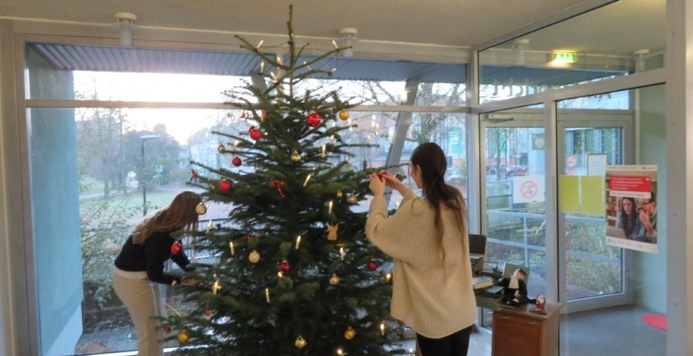 Fotografie zeigt Justizsekretäranwärterinnen beim Schmücken des Weihnachtsbaums